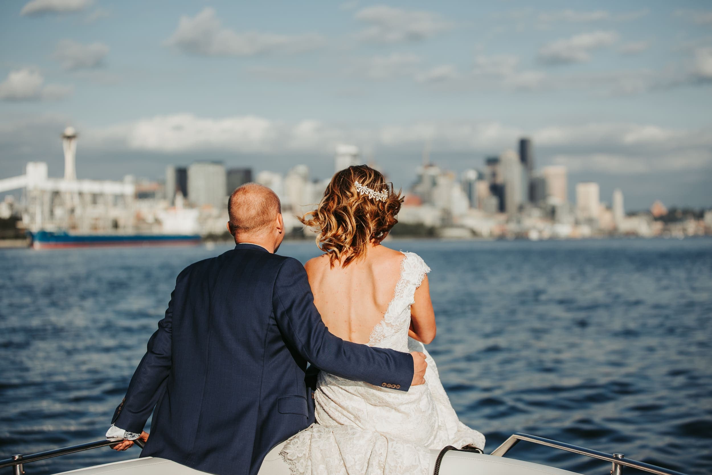 A bride and groom sitting on the edge of a boat in the water on their wedding day at The Edgewater