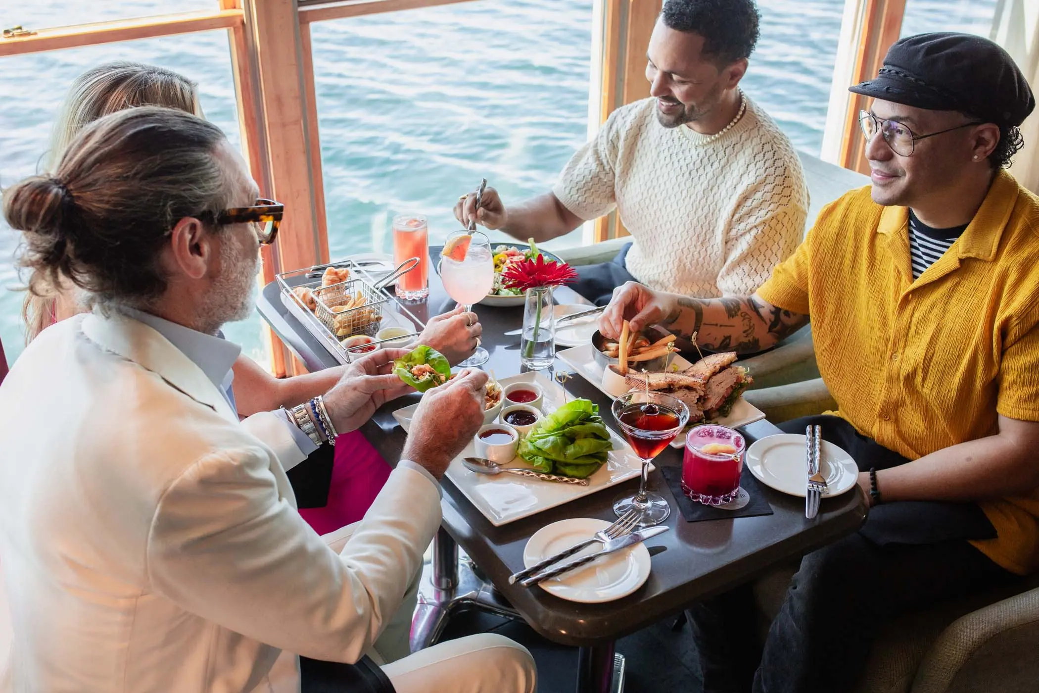 A group of people eating and drinking at Edgewater overlooking the water