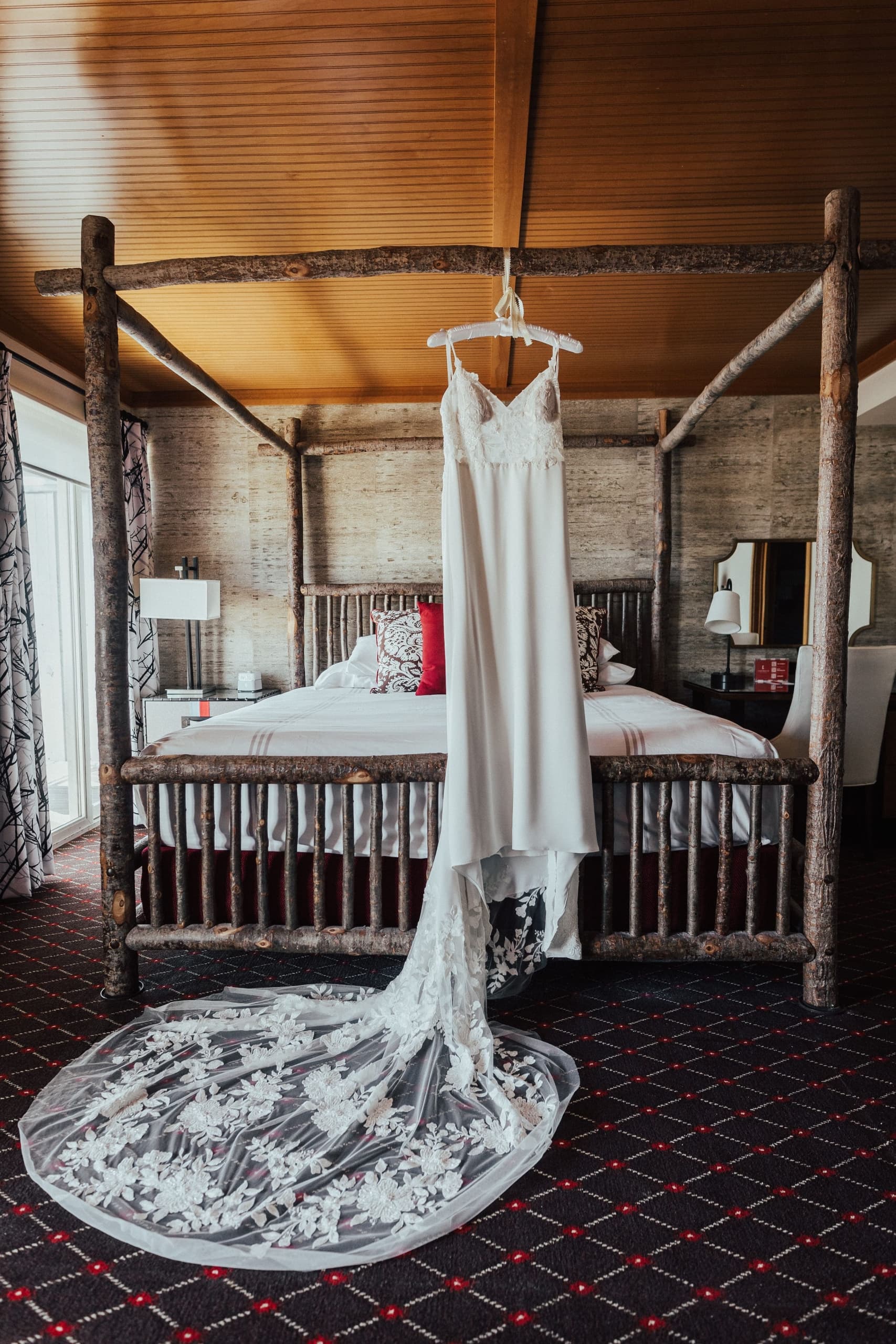 A beautiful and rustic suite at Edgewater with a brides dress hanging from the beds canopy.