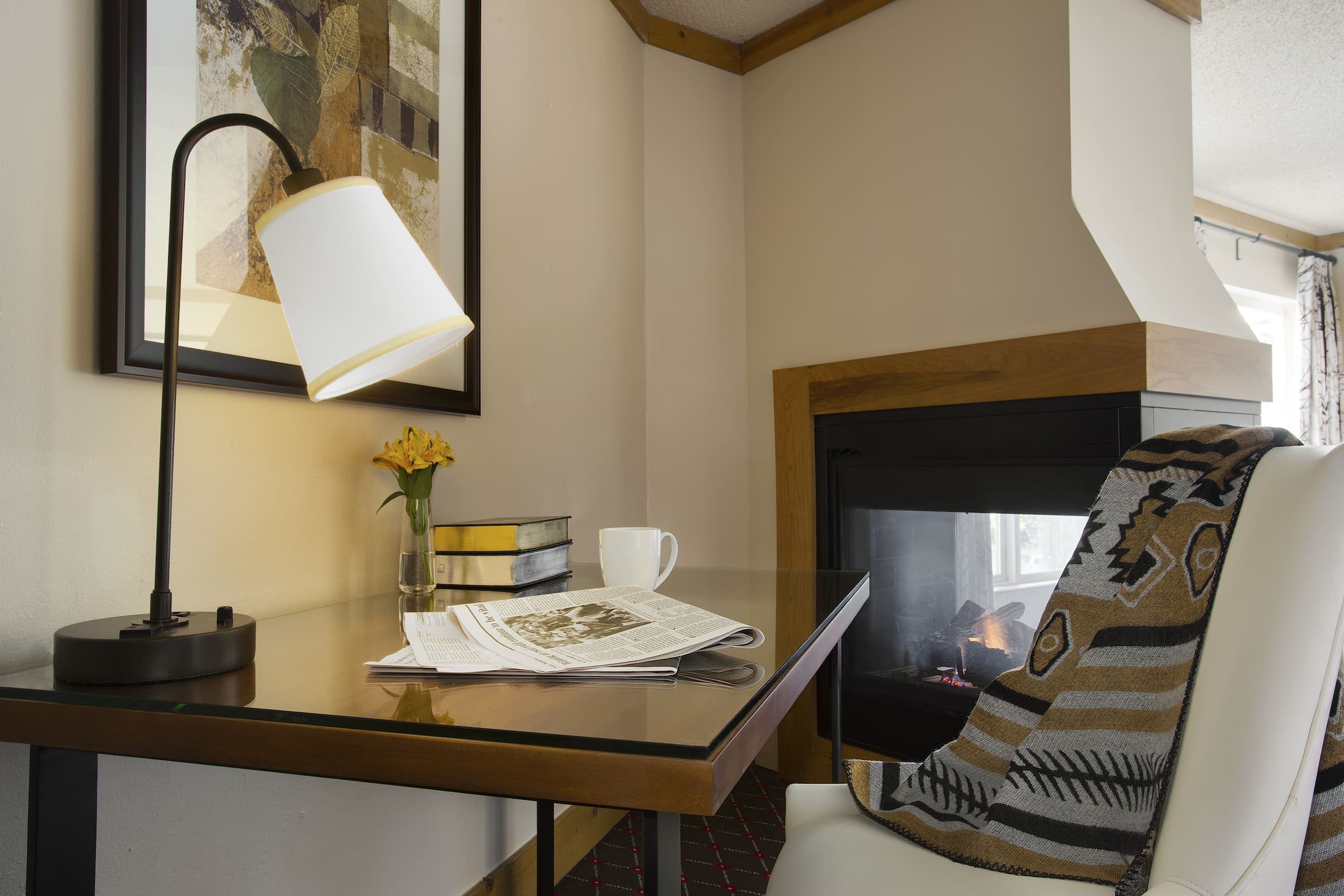 A desk with a lamp, newspaper and coffee cup on it, in a one bedroom at Edgewater