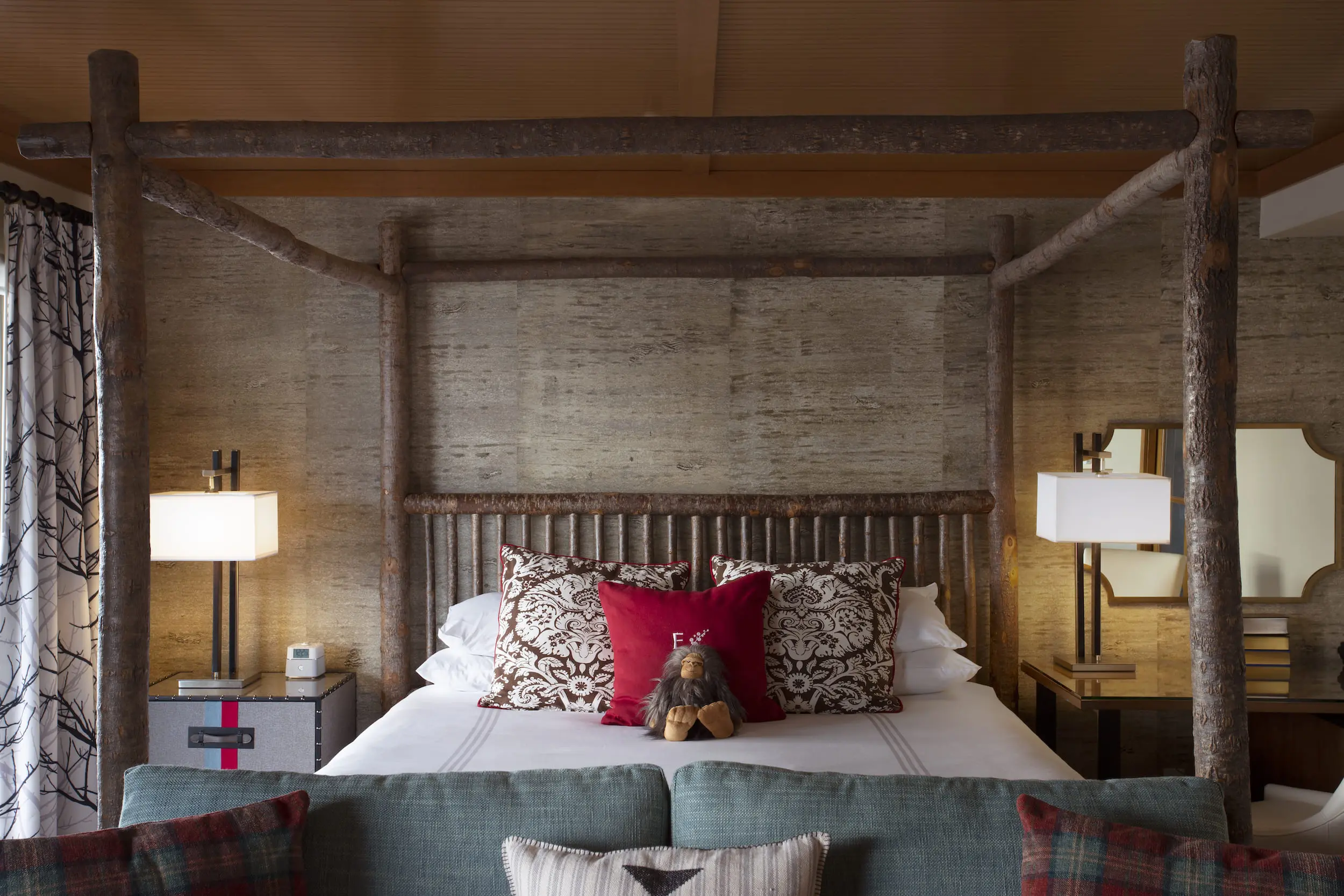 A bed in a Jr Suite at Edgewater with a raw wood canopy and 2 table lamps at Edgewater