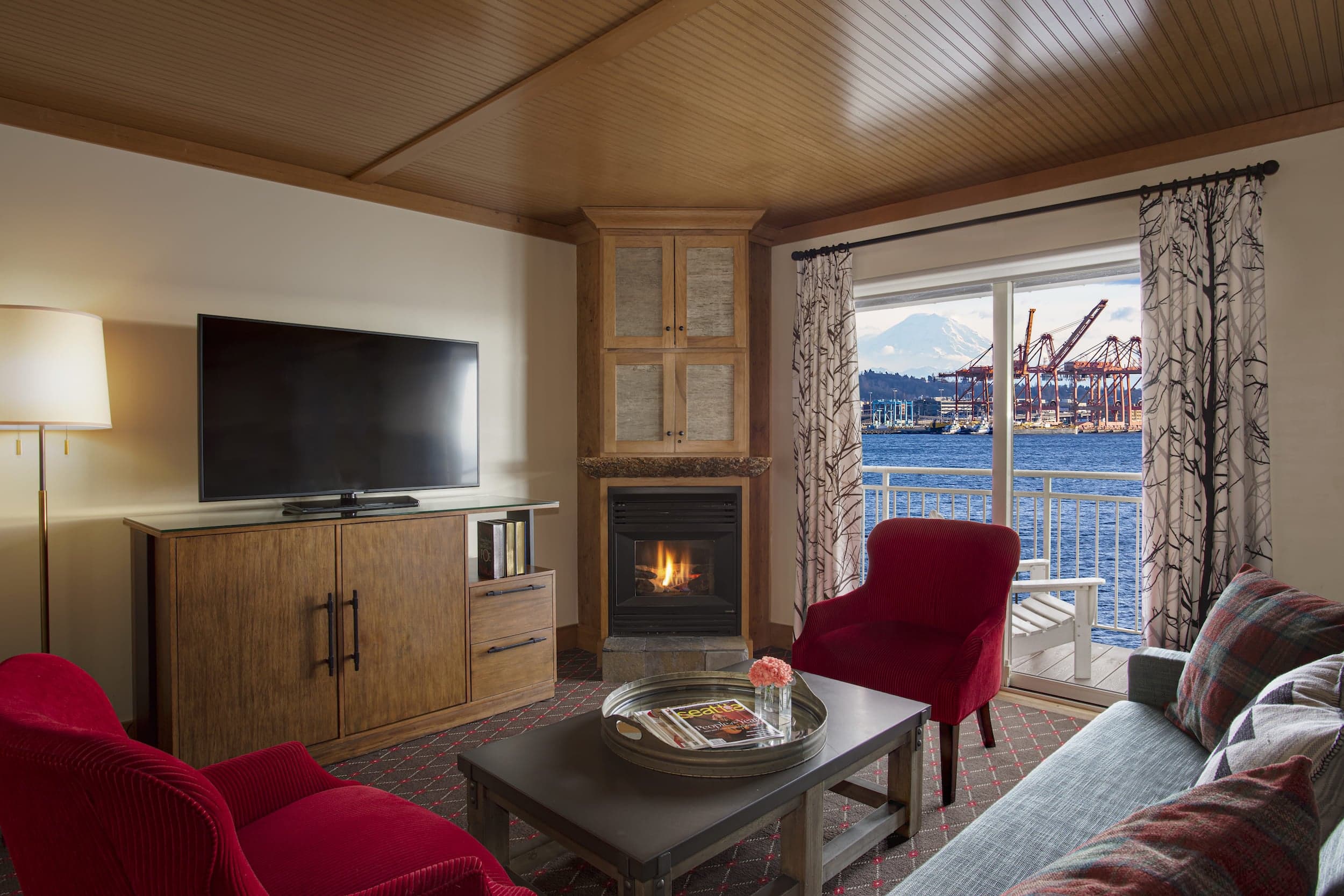 The living area with a TV, fireplace, couch, chairs, and coffee table with a view of the water in a Jr. Suite at Edgewater
