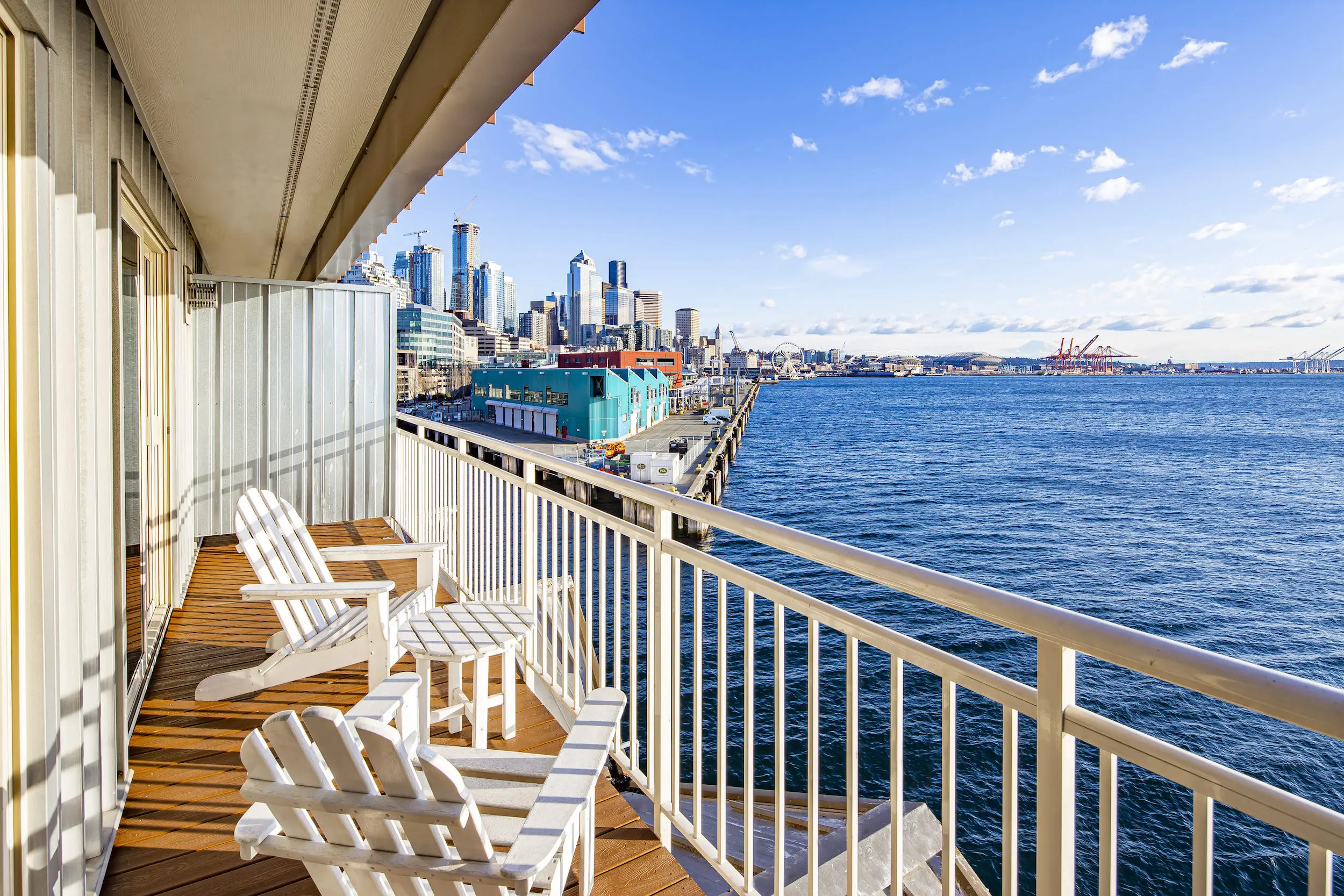 A large balcony with 2 chairs over looking the water with a view of the city at Edgewater