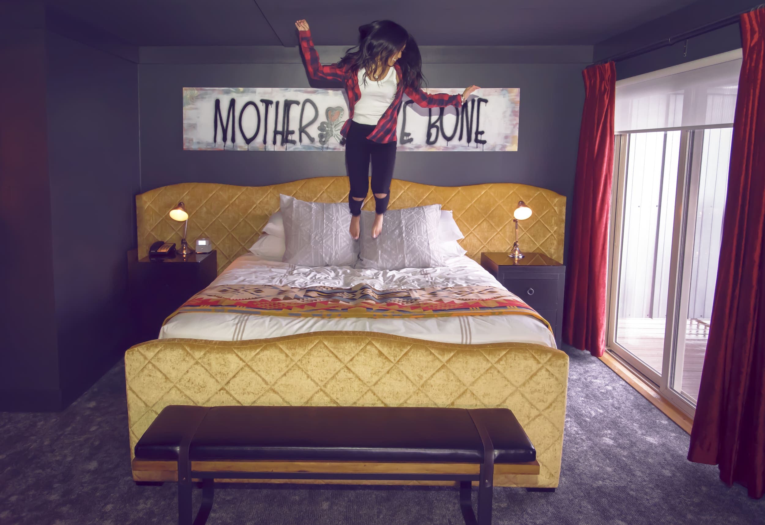 A woman jumping on the bed in the Pear Jam inspired room at Edgewater