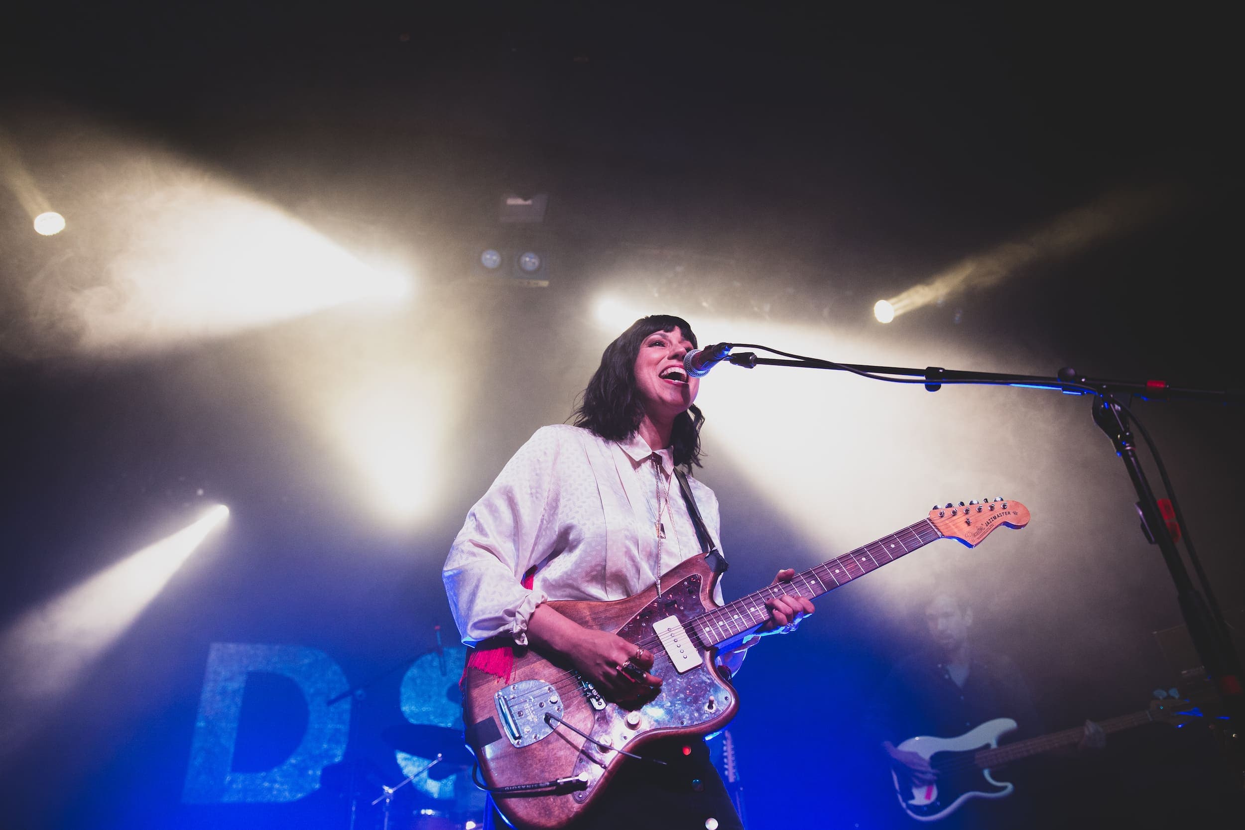 A woman on stage playing guitar and singing at a festival