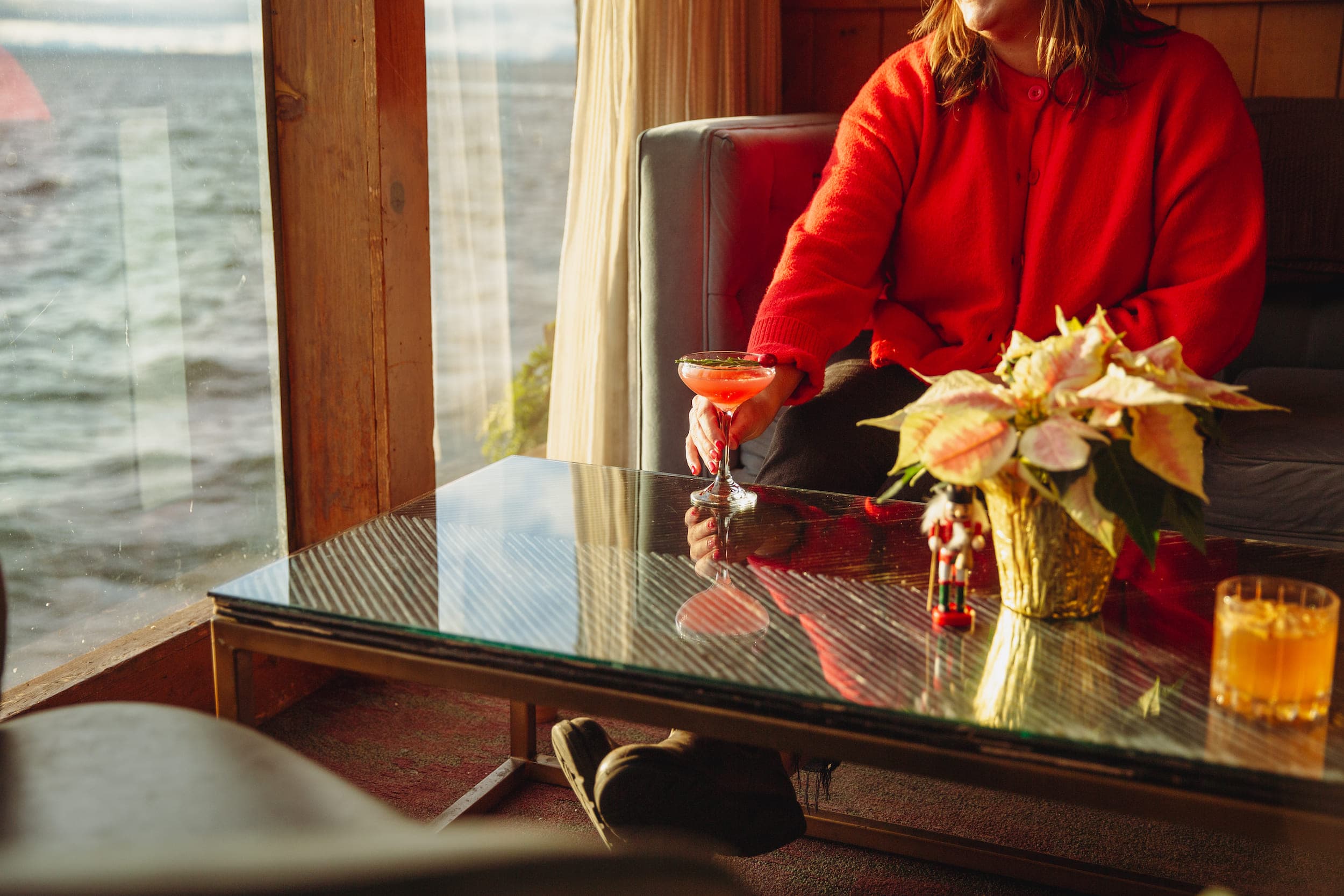 A woman sitting on a couch drinking a festive cocktail at Edgewater