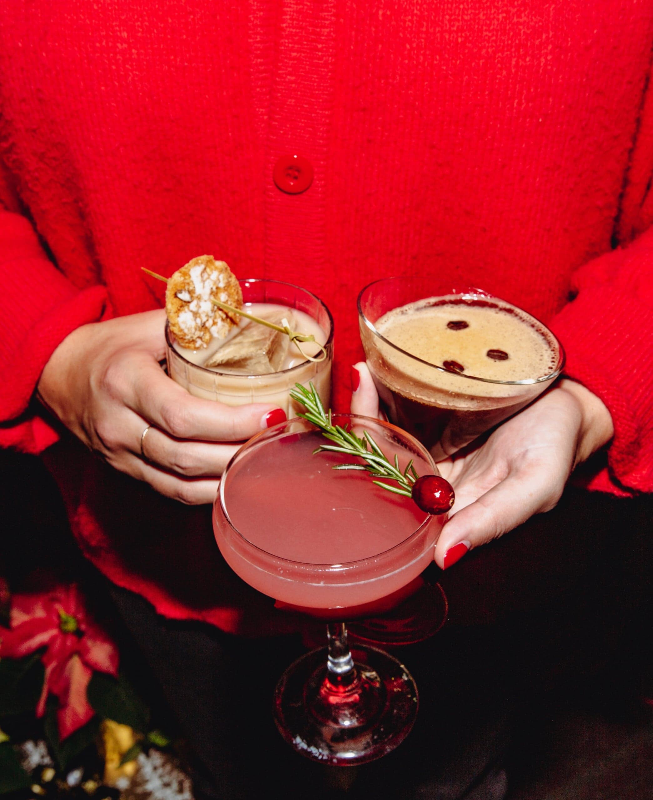 A person holding 3 cocktails