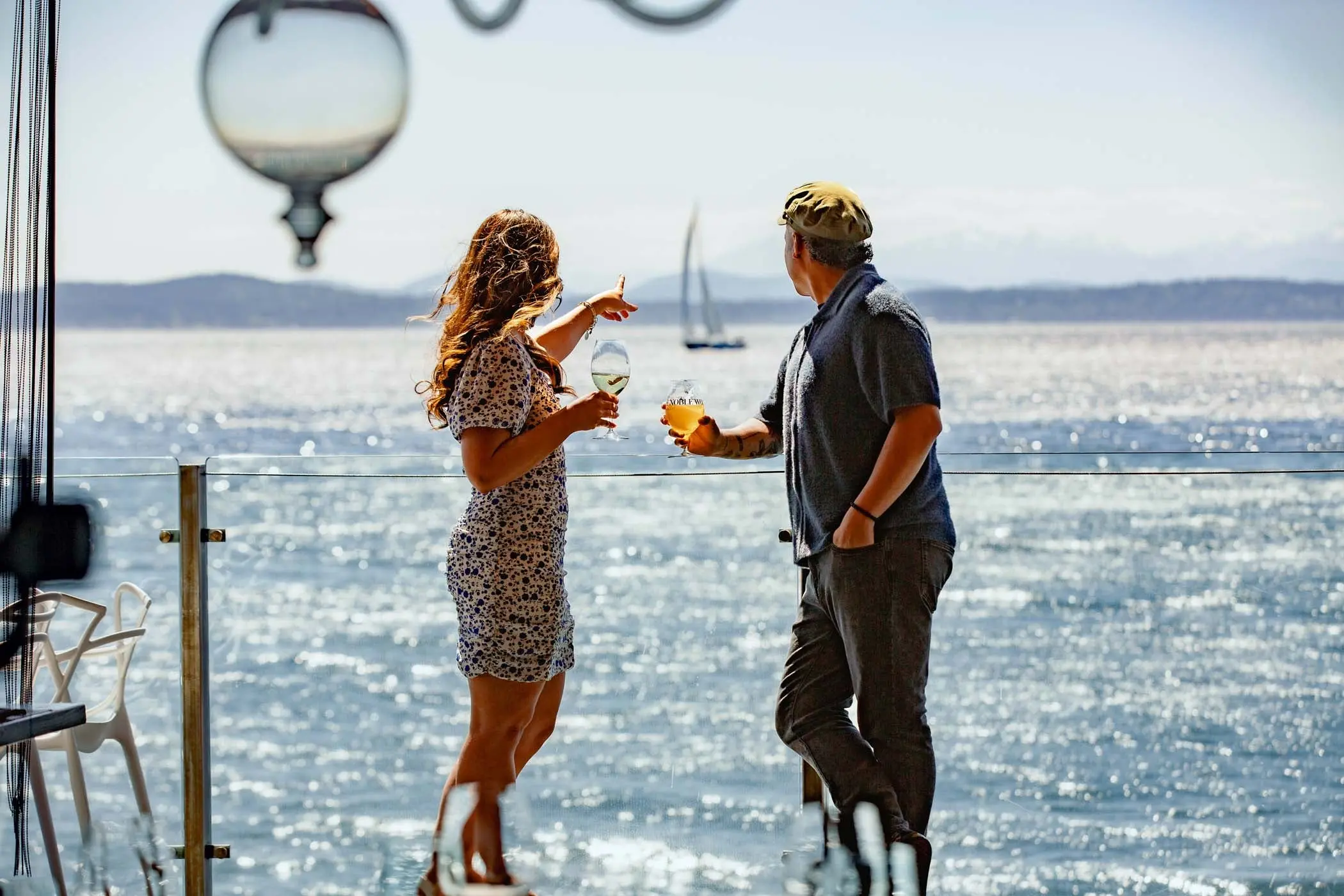 A man and a woman looking out to the water on the patio of the lobby bar at Edgewater