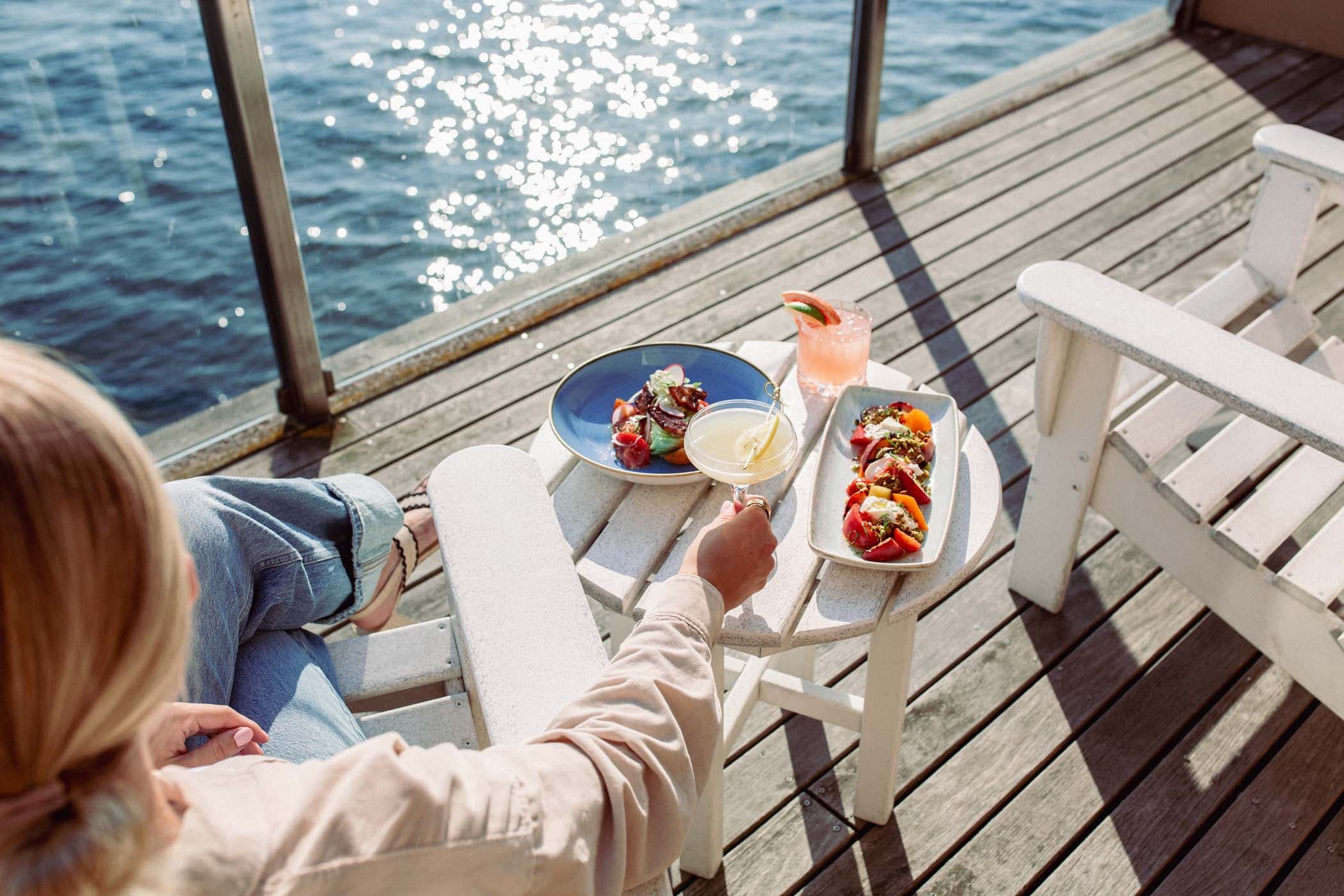 A person sitting on the balcony of their room while having a cocktail and some food at Edgewater