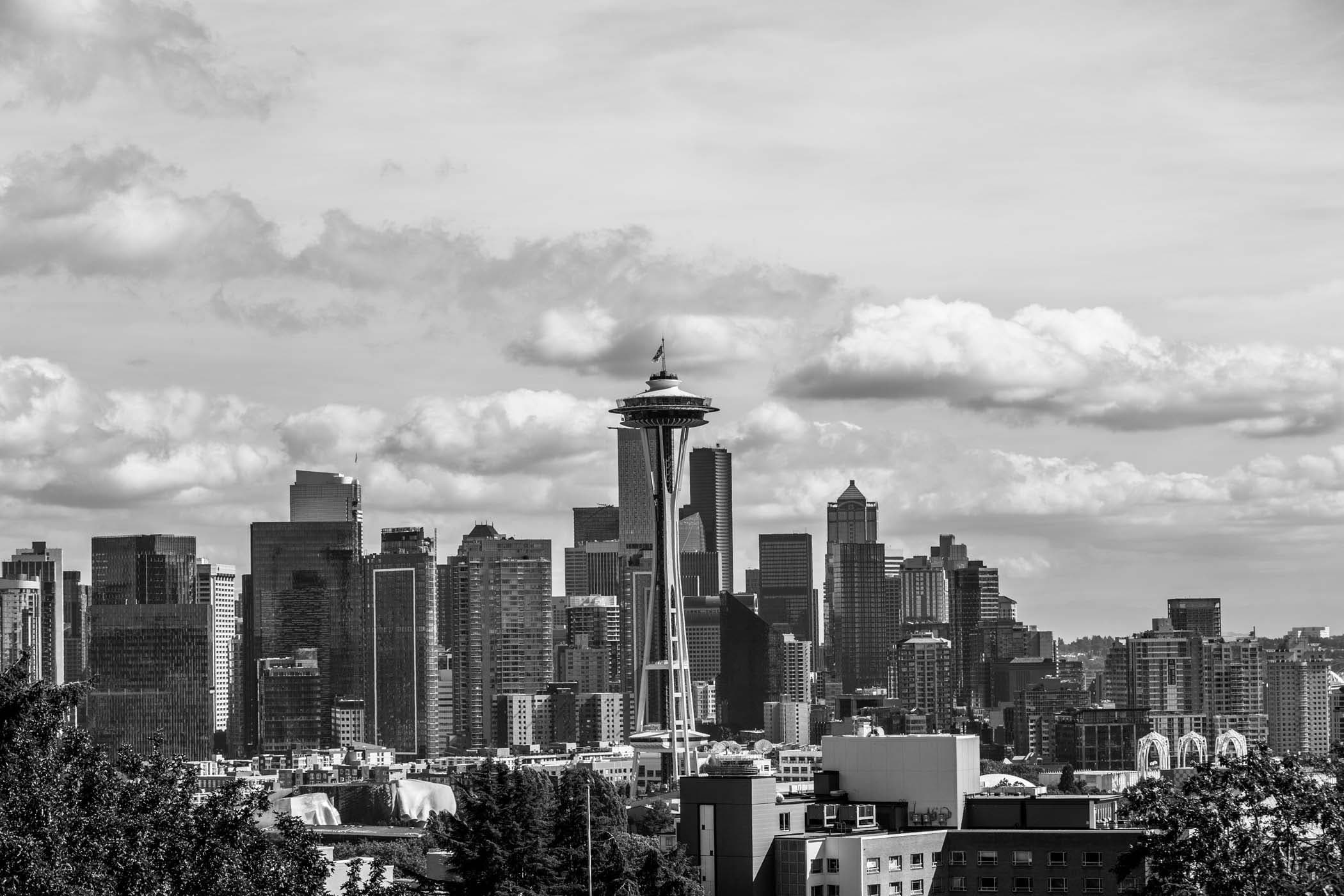 A black and white photo of the Space Needle in Seattle with large building in the background