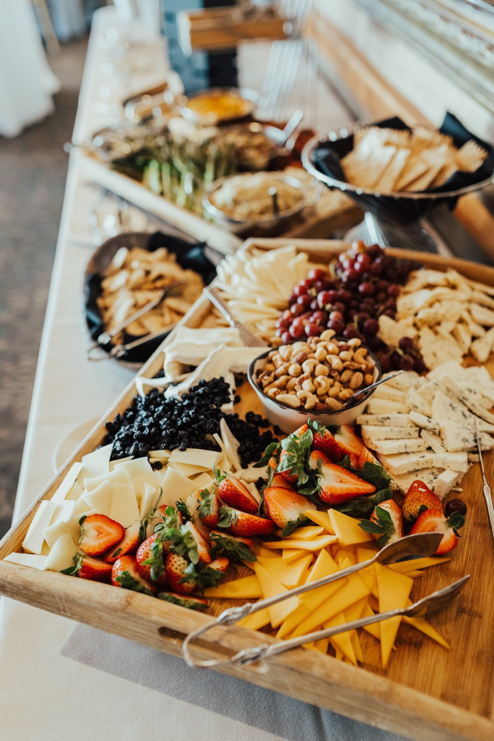 A board full of cheese, fruit, and nuts